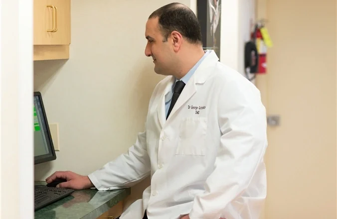 Dr. George Gotsiridze reviewing a patient's records at the computer.