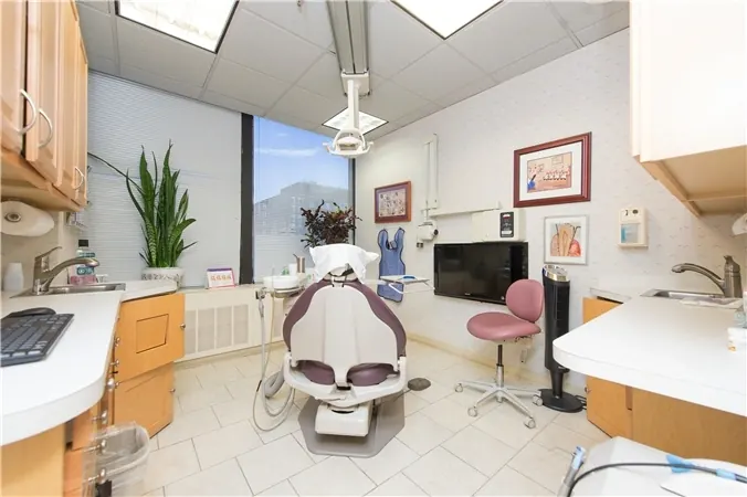 A treatment room at Bethesda Chevy Chase Advanced Dentistry, with the chair, a monitor on the wall and a window.